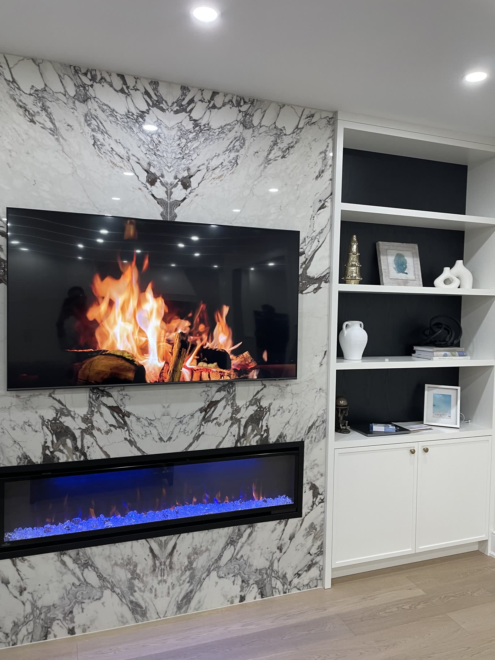 Marble fireplace wall with white cabinetry and black backed display shelving